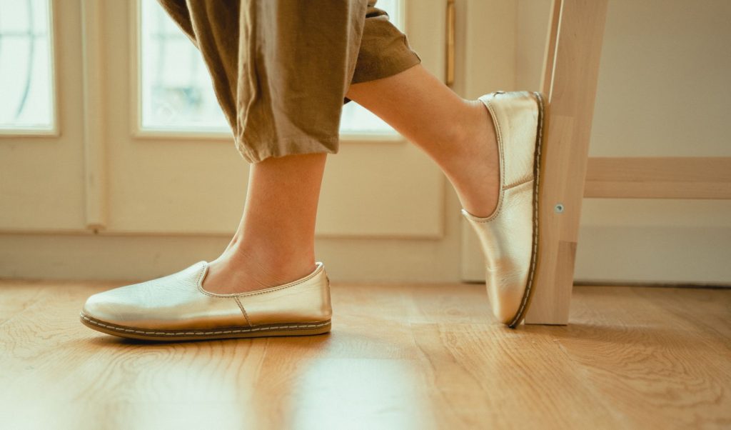 Chaussures plates dorées portées avec un pantalon kaki resserré au-dessus de la cheville