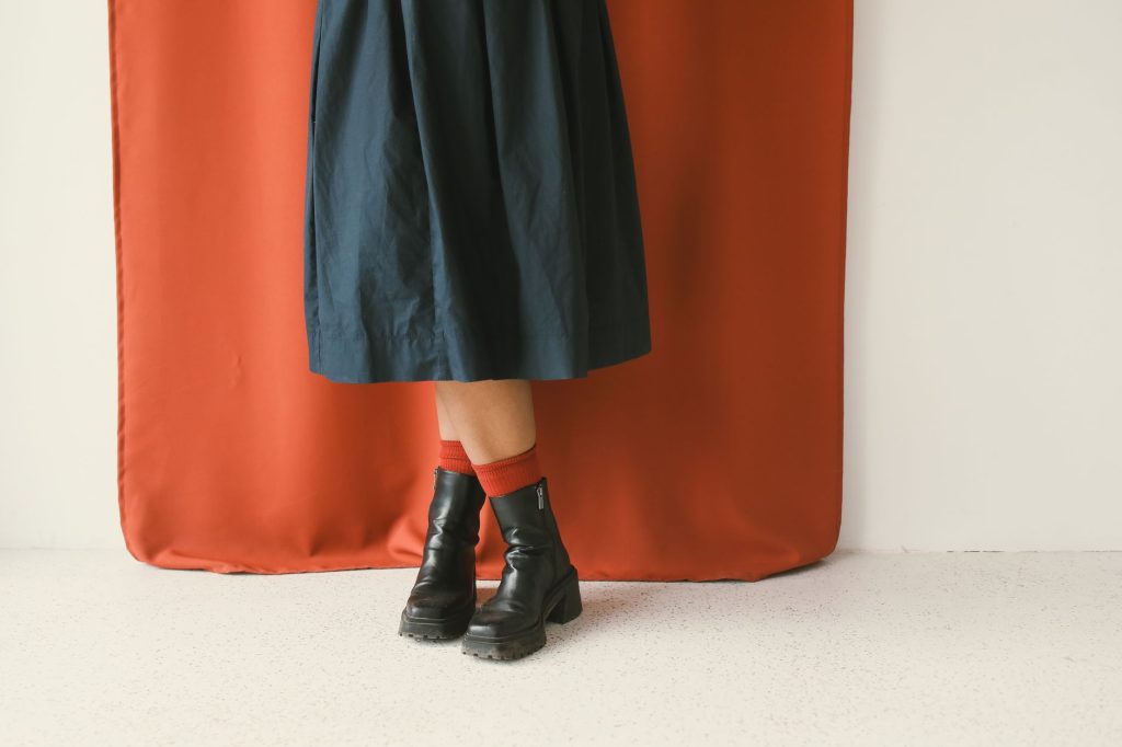 Jupe midi bleu nuit portée avec des bottines noires à lacets et des chaussettes rouges