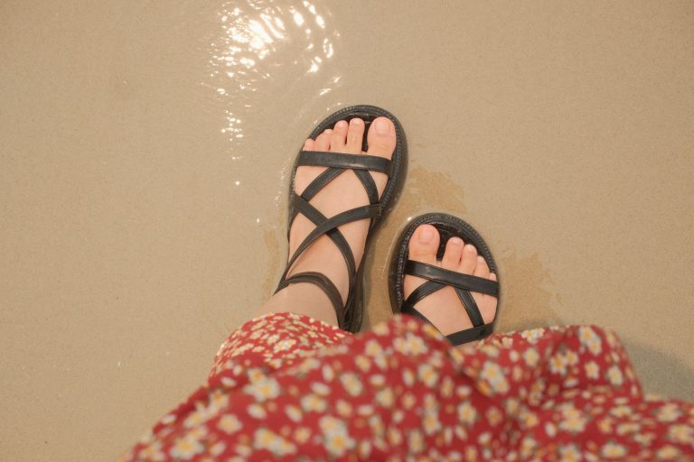 Sandales noires à brides vues de dessus sur un sol beige